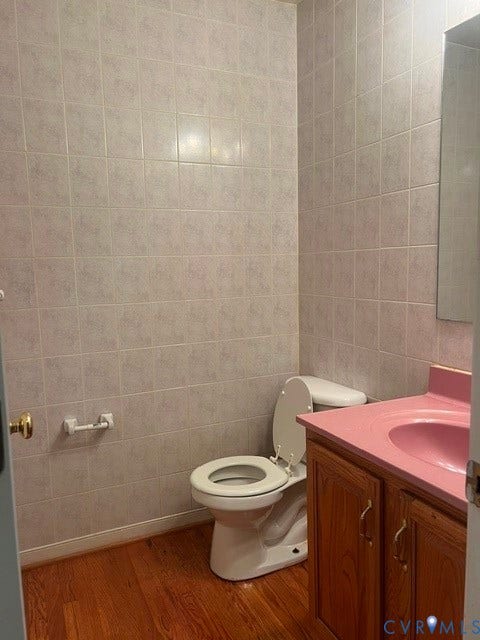 11419 Courthouse Acres Drive, Midlothian, VA 23114 Full wall tiling, wood-finish flooring, vanity with wood cabinetry, integrated basin sink, and a toilet