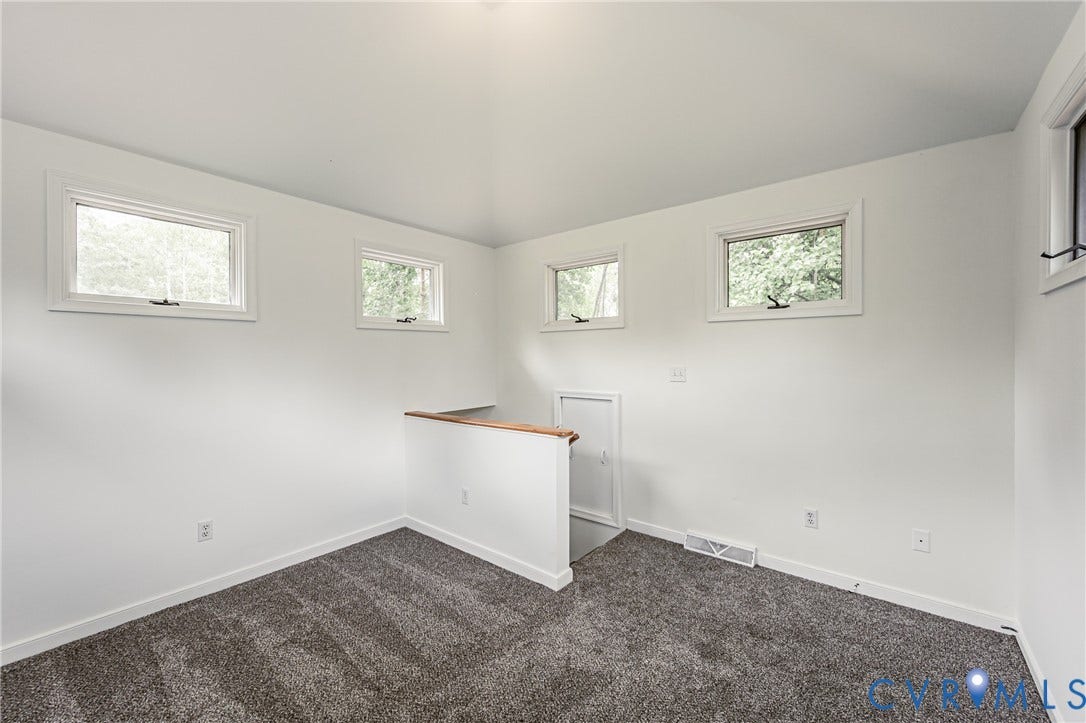 1520 Willow Brook Road, Louisa, VA 23024 Carpeted room featuring white walls, multiple windows, and a wood-capped half wall