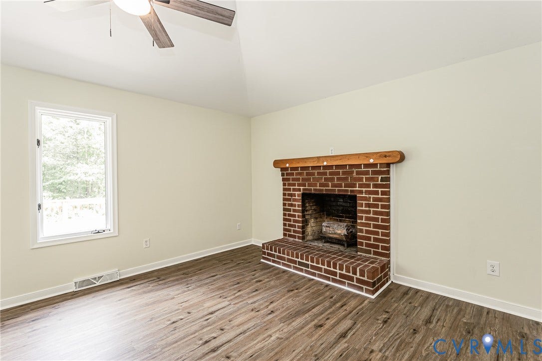 1520 Willow Brook Road, Louisa, VA 23024 LVP flooring, brick fireplace with wood mantel, white window trim, and a ceiling fan