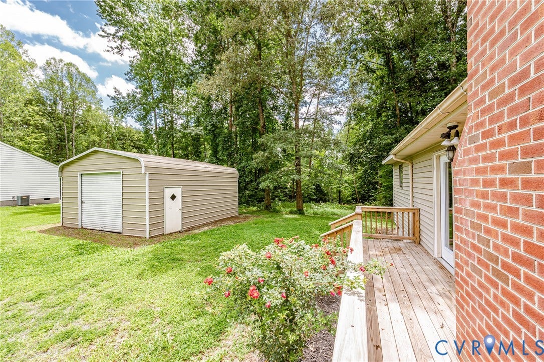 1520 Willow Brook Road, Louisa, VA 23024 Expansive backyard featuring a detached garage with a roll-up door, a secondary service door, a wood deck, and a brick exterior fireplace