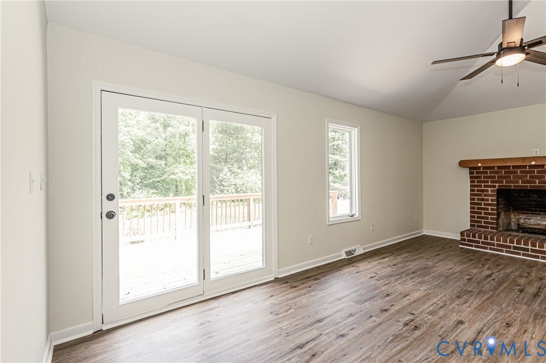 1520 Willow Brook Road, Louisa, VA 23024 LVP flooring, brick fireplace with wood mantel, vaulted ceiling, and dual-pane glass doors leading to a wood deck