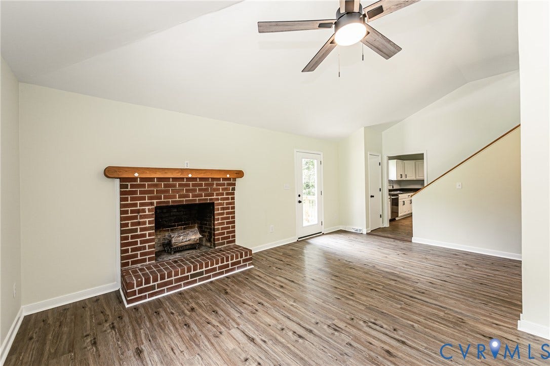 1520 Willow Brook Road, Louisa, VA 23024 Spacious room featuring LVP flooring, a brick fireplace with a wood mantle, and a ceiling fan with integrated lighting