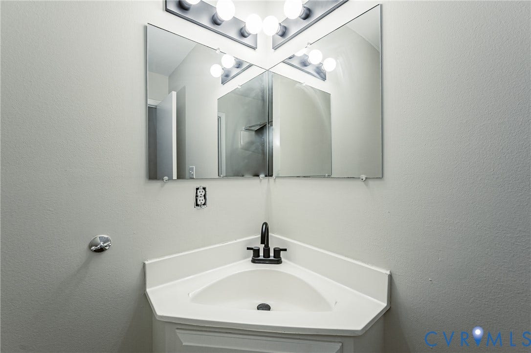 1520 Willow Brook Road, Louisa, VA 23024 Corner vanity with an integrated sink, matte black faucet, and dual wall-mounted mirrors