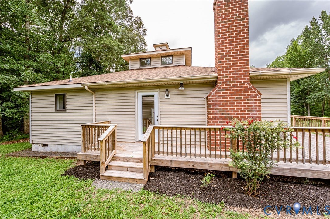 1520 Willow Brook Road, Louisa, VA 23024 Exterior featuring light-toned siding, a multi-level wooden deck with railings, a brick chimney, and a multi-pane glass-panel door