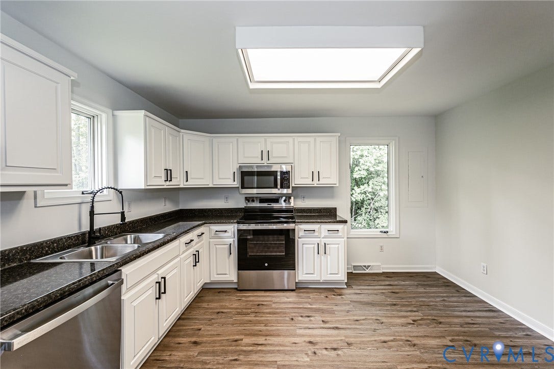 1520 Willow Brook Road, Louisa, VA 23024 White shaker cabinetry with dark hardware, stainless steel appliances, dark countertops, and a large ceiling light fixture