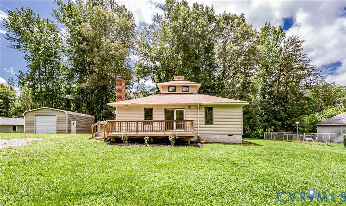 1520 Willow Brook Road, Louisa, VA 23024 Expansive backyard featuring a large wood deck, tan siding, red brick chimney, and a detached metal garage