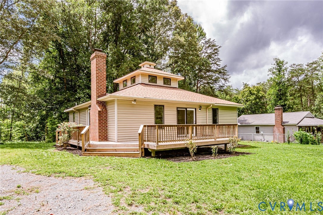 1520 Willow Brook Road, Louisa, VA 23024 Exterior featuring a deck, prominent brick chimney, circular architectural element with windows, and a surrounding natural landscape