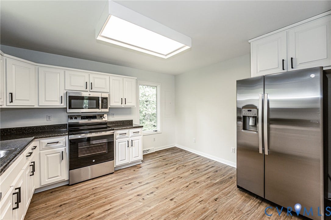 1520 Willow Brook Road, Louisa, VA 23024 White cabinetry with black hardware, stainless steel appliances, dark countertops, and a large rectangular ceiling light fixture