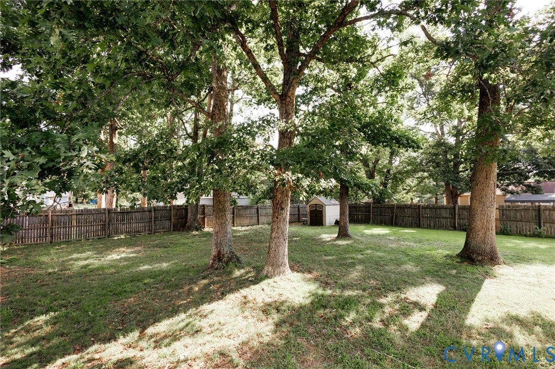 15525 Saddlebrook Road, Chesterfield, VA 23838 Expansive grassy yard featuring mature trees, a full wood privacy fence, and a storage shed