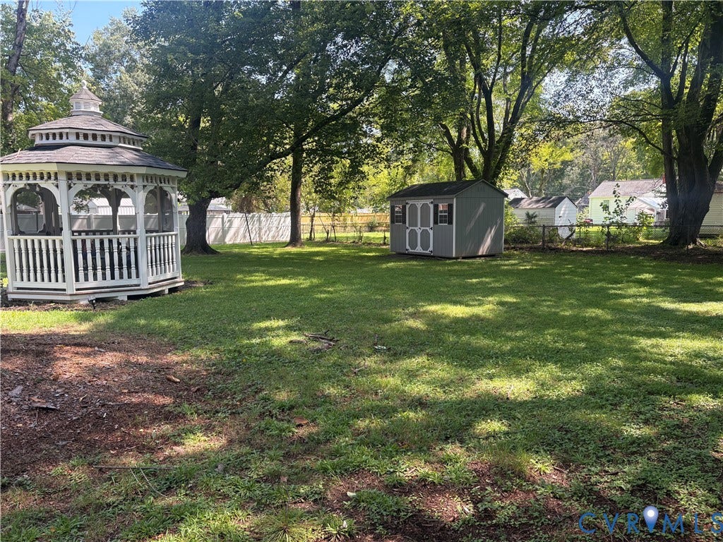 2443 Tignor Road, Richmond, VA 23224 Expansive outdoor space featuring a white gazebo, a storage shed, established trees, and a wire fence
