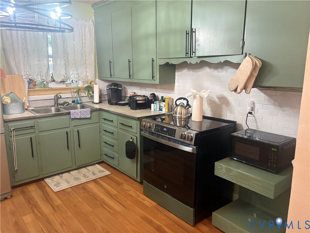 2443 Tignor Road, Richmond, VA 23224 Green cabinetry with black hardware, wood-finish flooring, subway tile backsplash, stainless steel double basin sink, and a black range