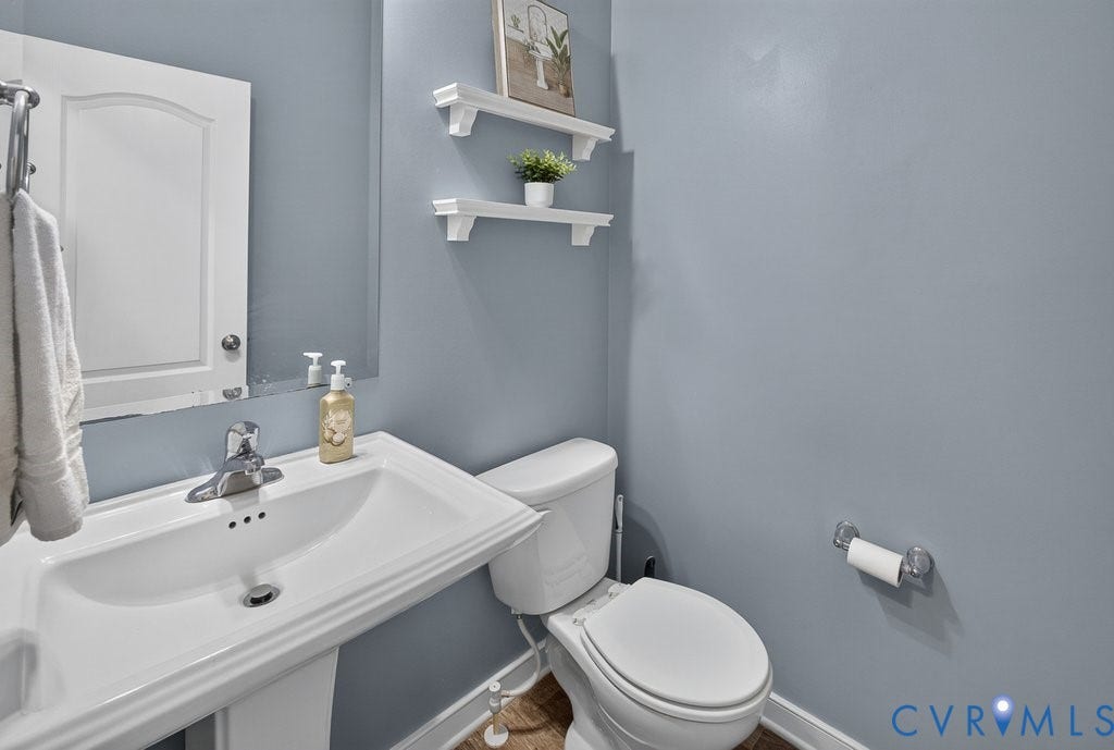 7401 Nicklaus Circle, Moseley, VA 23120 First Floor 1/2 Bath. Pedestal sink with chrome faucet, wall-mounted mirror, white wall cabinetry, and coordinating wall-mounted shelving.