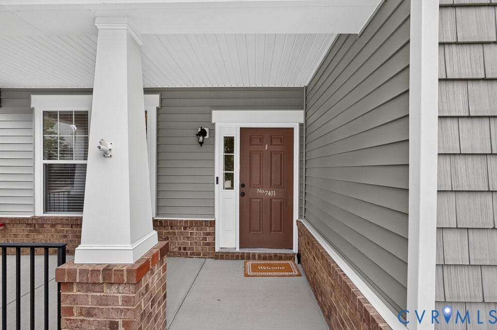 7401 Nicklaus Circle, Moseley, VA 23120 Covered front entry featuring a brown paneled door, horizontal siding, and a brick facade