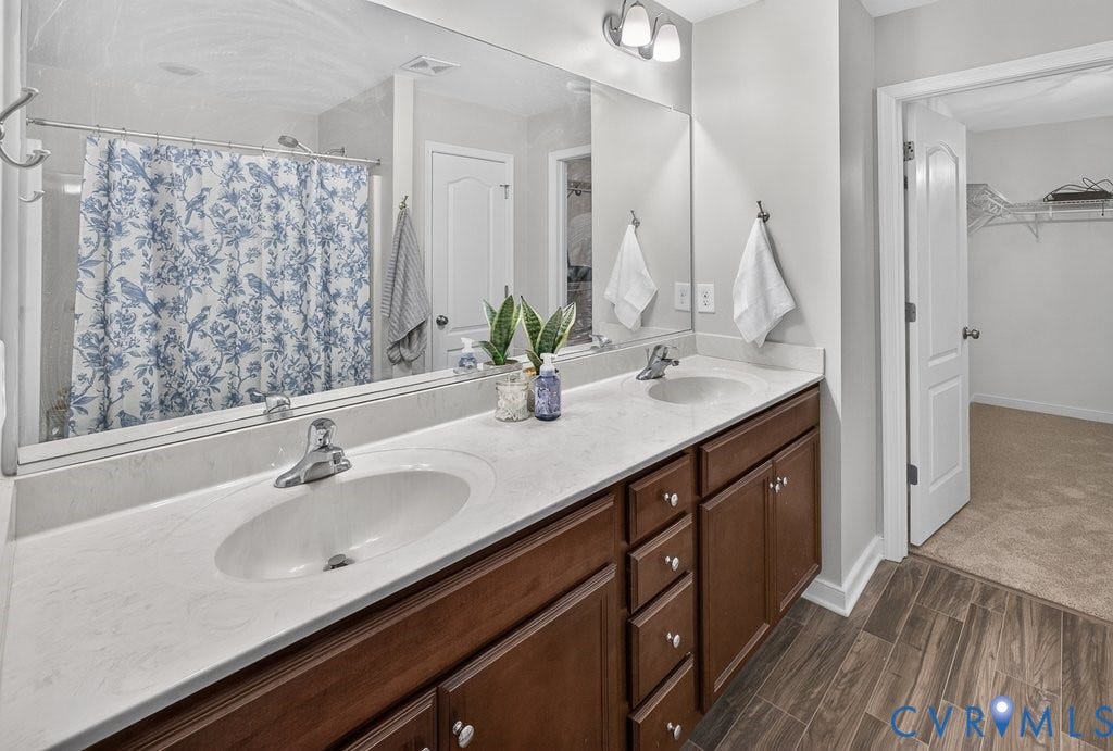 7401 Nicklaus Circle, Moseley, VA 23120 Double vanity with integrated sinks, wood-finish cabinetry, and a full-width mirror