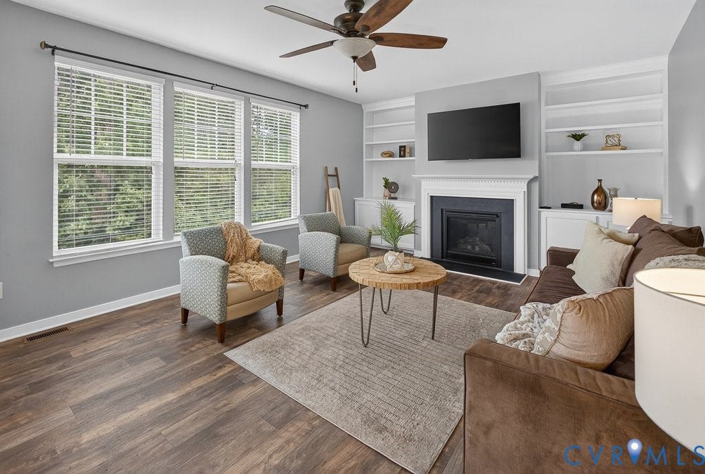 7401 Nicklaus Circle, Moseley, VA 23120 Hardwood-finish flooring, built-in shelving, fireplace with mantel, ceiling fan, and multiple windows with blinds.