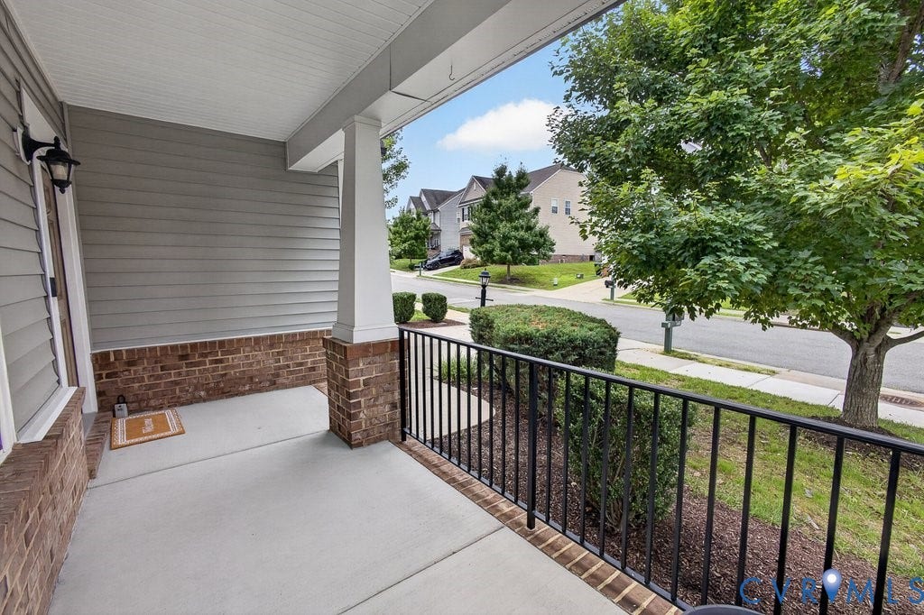 7401 Nicklaus Circle, Moseley, VA 23120 Covered concrete porch featuring a white support column, brick detailing, gray siding, and a black metal railing