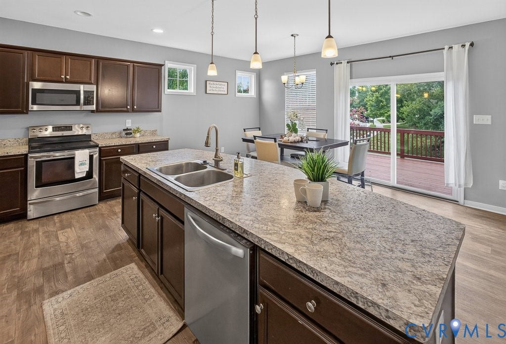 7401 Nicklaus Circle, Moseley, VA 23120 Kitchen featuring dark wood-finish cabinetry, stainless steel appliances, a center island with a double basin sink, and wood-finish flooring