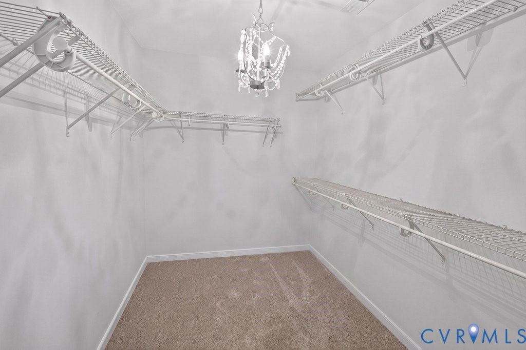 7401 Nicklaus Circle, Moseley, VA 23120 First of 2 Primary Closets. Walk-in closet featuring carpet flooring, white wire shelving, and a decorative chandelier.