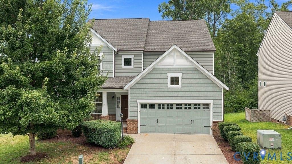 7401 Nicklaus Circle, Moseley, VA 23120 Two-story exterior with light gray siding and shingle accents, attached garage with a light green door, concrete driveway, and covered front entry