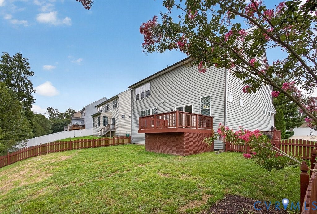 7401 Nicklaus Circle, Moseley, VA 23120 Expansive outdoor space featuring a wood deck, brown picket fencing, and a grassy lawn