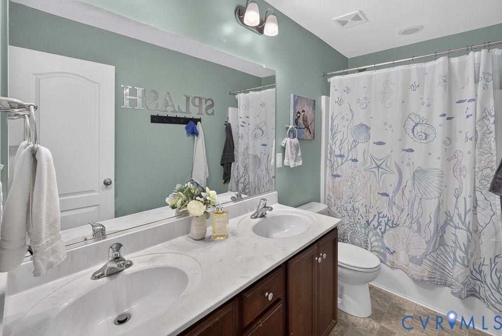 7401 Nicklaus Circle, Moseley, VA 23120 Dual vanity with integrated sinks, white countertops, dark wood-finish cabinetry, and a shower-tub combination