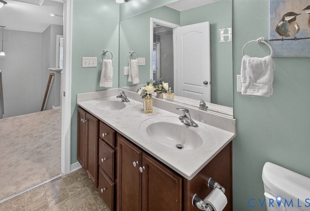 7401 Nicklaus Circle, Moseley, VA 23120 Double vanity with integrated sinks, dark wood-finish cabinetry, and a large wall-mounted mirror