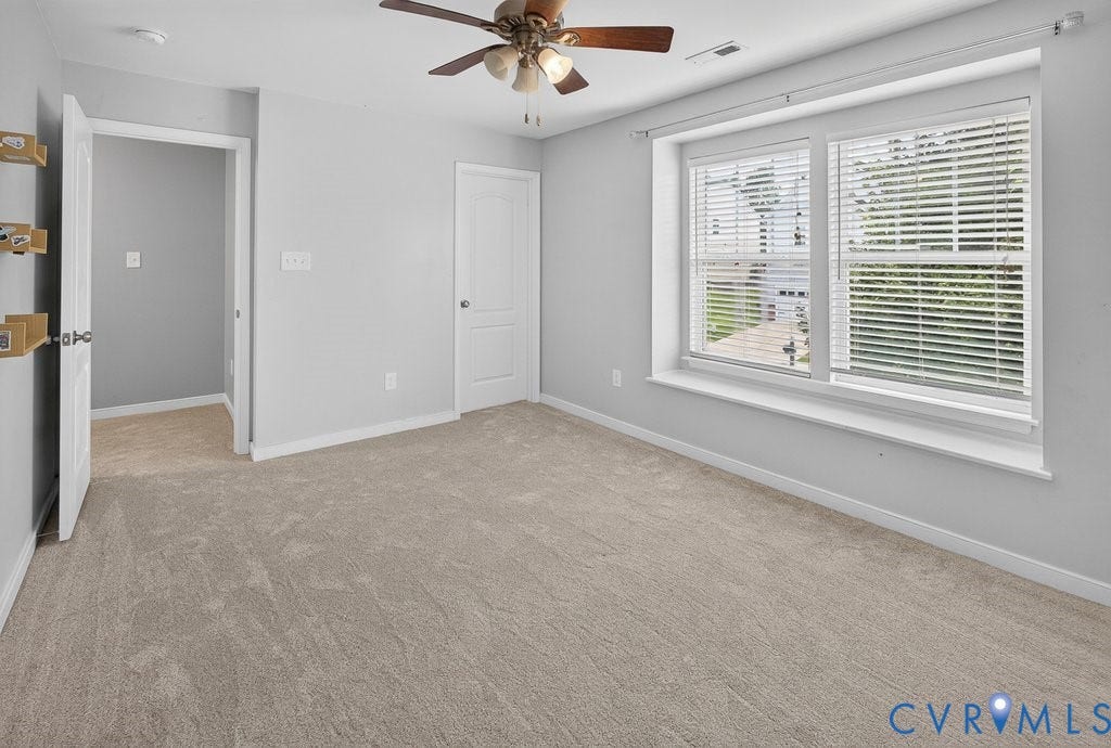 7401 Nicklaus Circle, Moseley, VA 23120 Bedroom 3 - Neutral-toned carpeting, ample natural light through a large window, a ceiling fan, and two panel doors