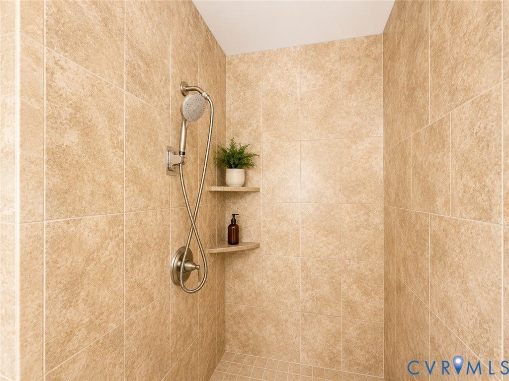 9018 Brucewood Drive, Midlothian, VA 23235 Tiled shower enclosure featuring a handheld showerhead, brushed nickel fixtures, and built-in corner shelving