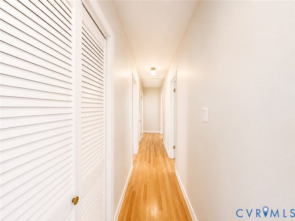 9018 Brucewood Drive, Midlothian, VA 23235 Hardwood flooring extends throughout the hallway, featuring white louvered closet doors and a flush-mount ceiling light fixture