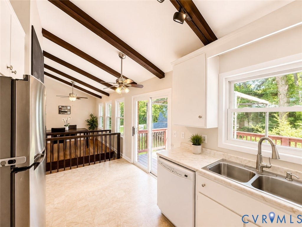 9018 Brucewood Drive, Midlothian, VA 23235 Vaulted ceilings with exposed wood beams, stainless steel appliances, white cabinetry, double basin sink, and a sliding glass door to an outdoor area