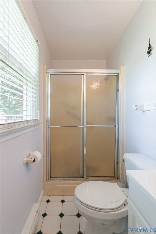 2730 Kinvan Road, Henrico, VA 23231 Shower enclosure with sliding frosted glass doors, white toilet, and patterned floor tiling