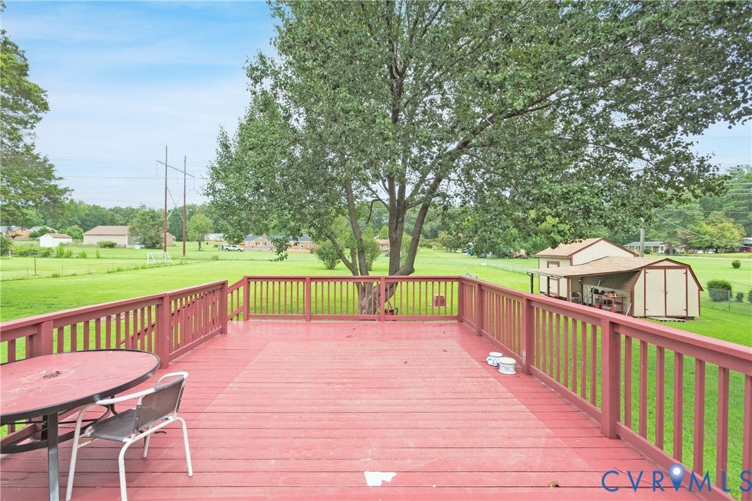 2730 Kinvan Road, Henrico, VA 23231 Expansive red-stained wooden deck featuring a full railing, overlooking a large grassy area with mature trees