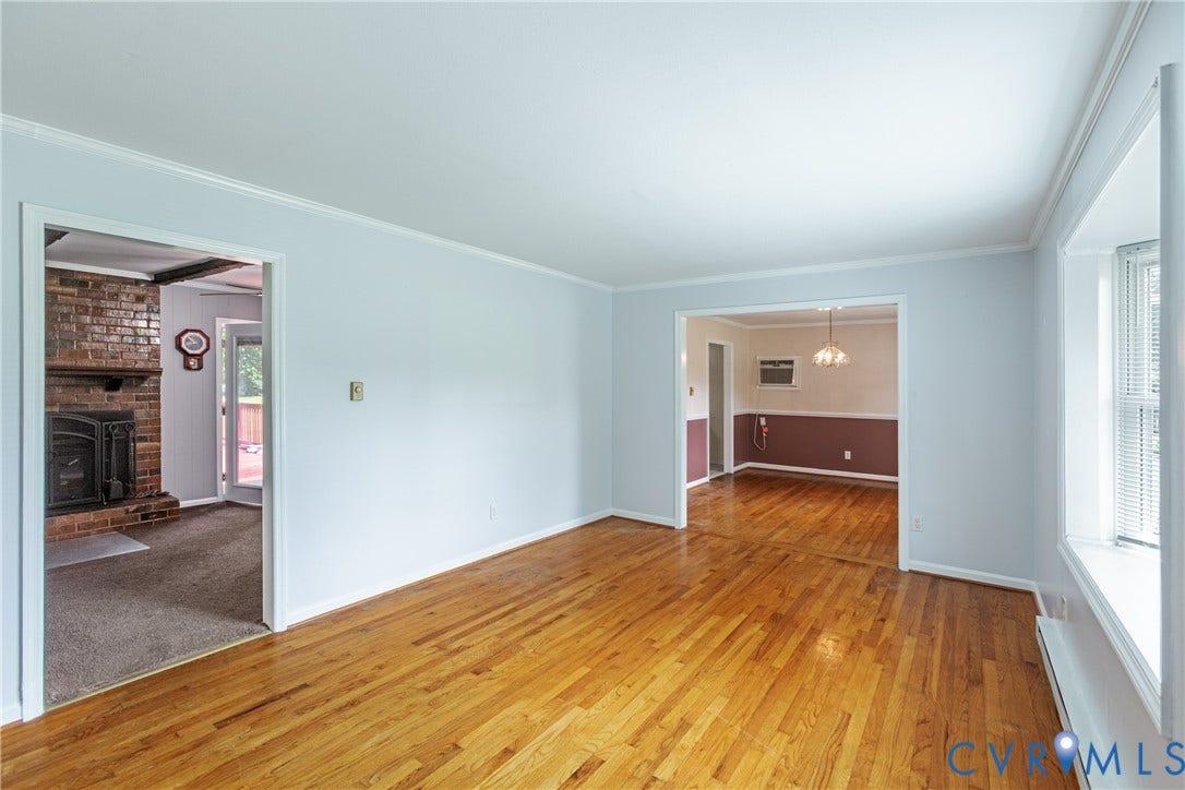 2730 Kinvan Road, Henrico, VA 23231 Hardwood flooring, crown molding, a brick fireplace with a hearth, and a dining area with a chandelier