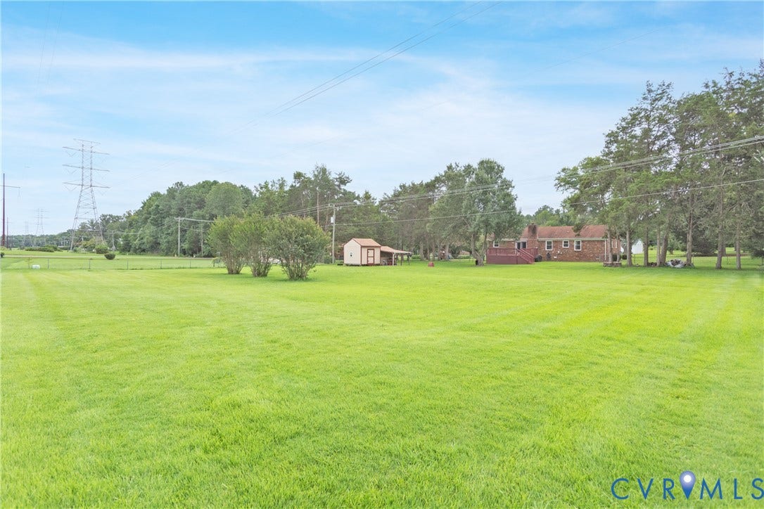 2730 Kinvan Road, Henrico, VA 23231 Expansive grassy yard with mature trees, a red brick home with a rear deck, and a detached shed