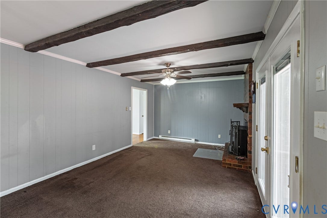 2730 Kinvan Road, Henrico, VA 23231 Exposed ceiling beams, brick fireplace with mantel, ceiling fan with light fixture, light gray wall paneling, and double French doors