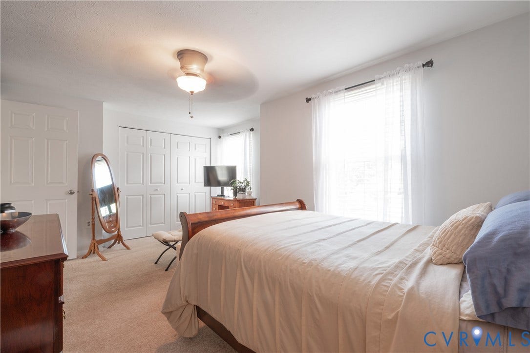 Carpeted flooring, ceiling fan with integrated lighting, window with sheer curtains, and bi-fold closet doors