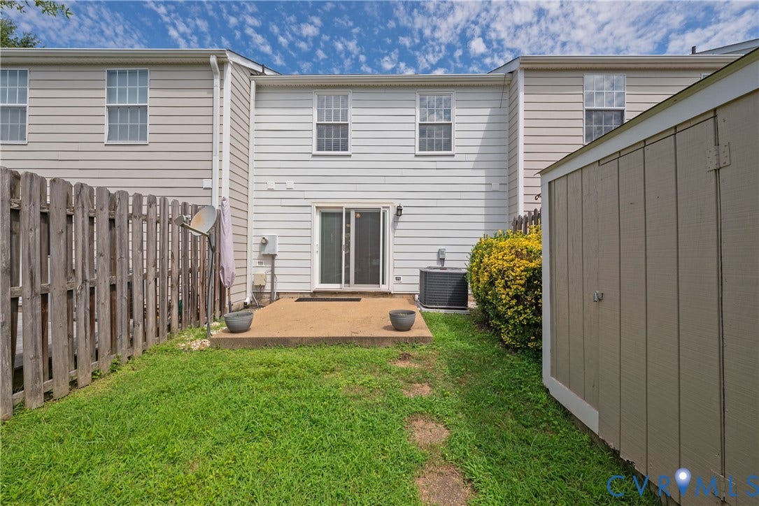 Fenced backyard featuring a concrete patio, grassy area, and exterior storage shed
