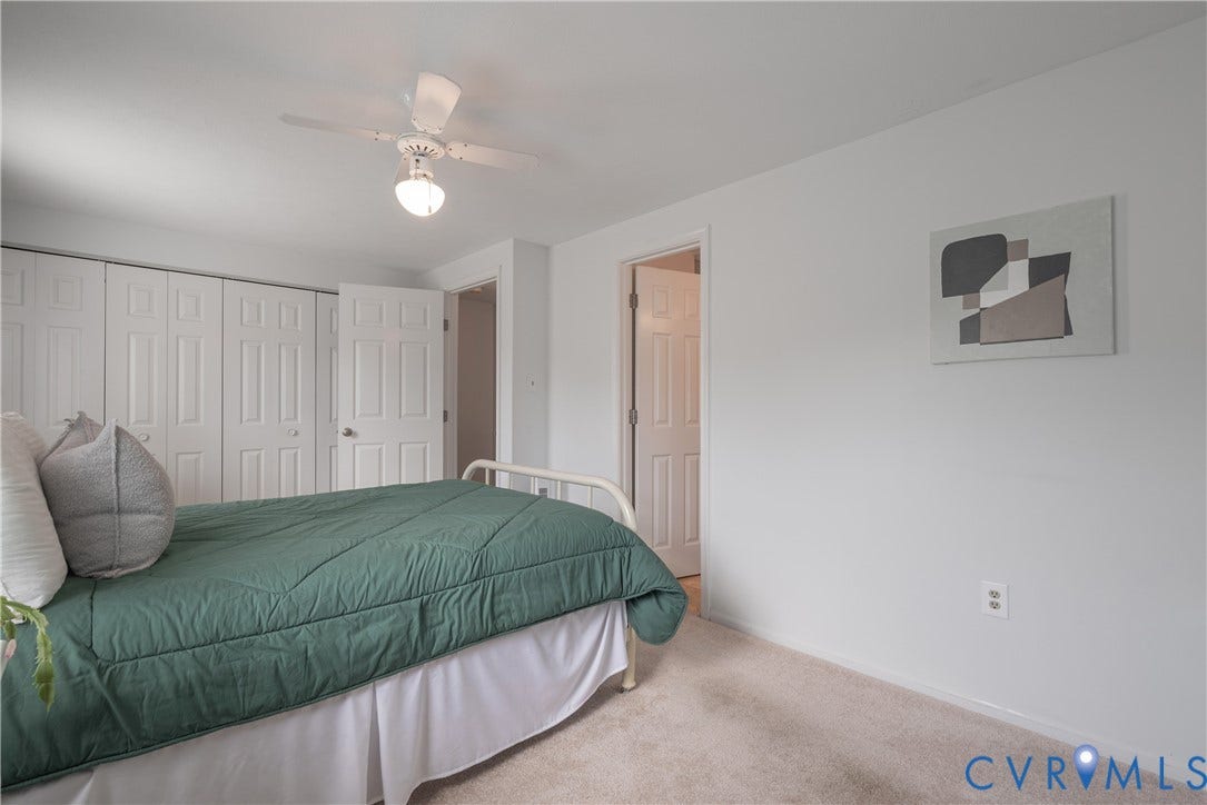 White walls, carpeted flooring, and a ceiling fan with integrated lighting