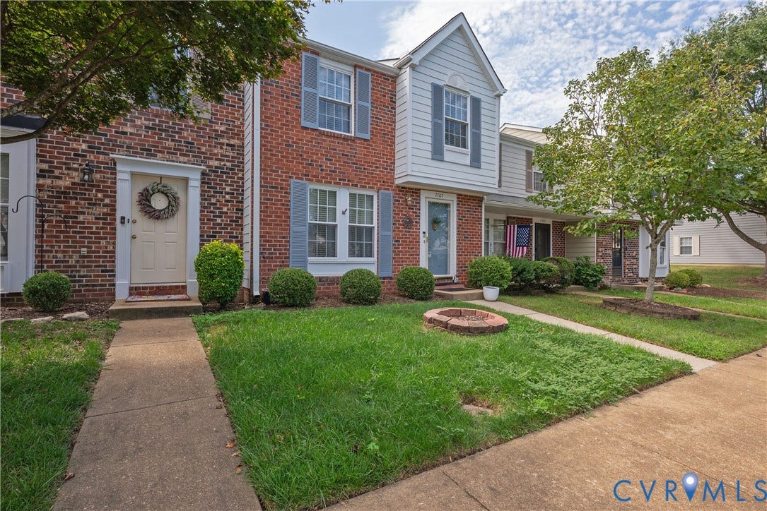 Brick and siding exterior with shutters, concrete walkways, and mature landscaping
