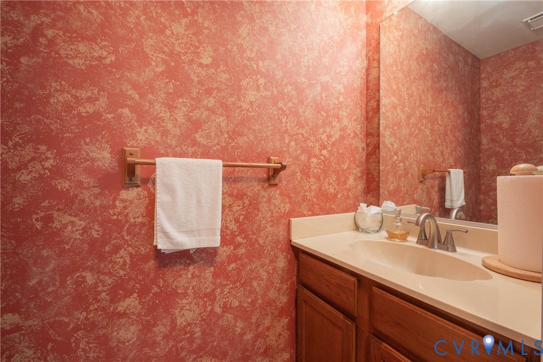 Built-in vanity with a single basin sink, brushed nickel faucet, and wood-finish cabinetry