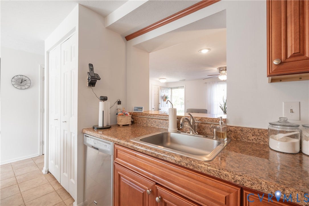 Kitchen featuring a stainless steel sink, a stainless steel dishwasher, wood-finish cabinetry, and a stone-finish countertop