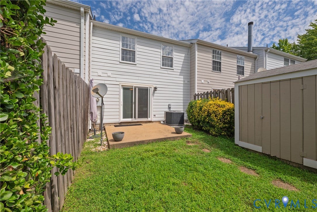 Rear exterior featuring a concrete patio, sliding glass door, and a detached storage shed