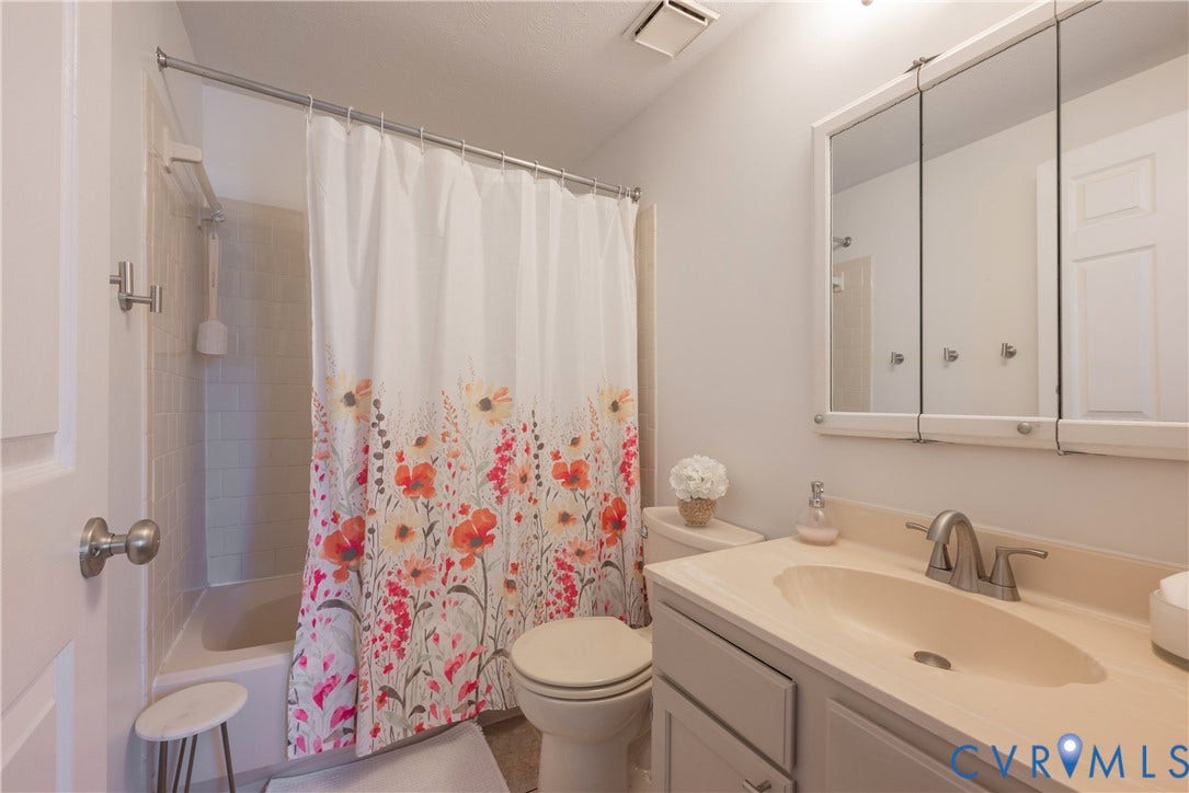 Bathroom featuring a vanity with an integrated sink, tri-fold mirrored medicine cabinet, and a shower-over-tub combination with tiled walls