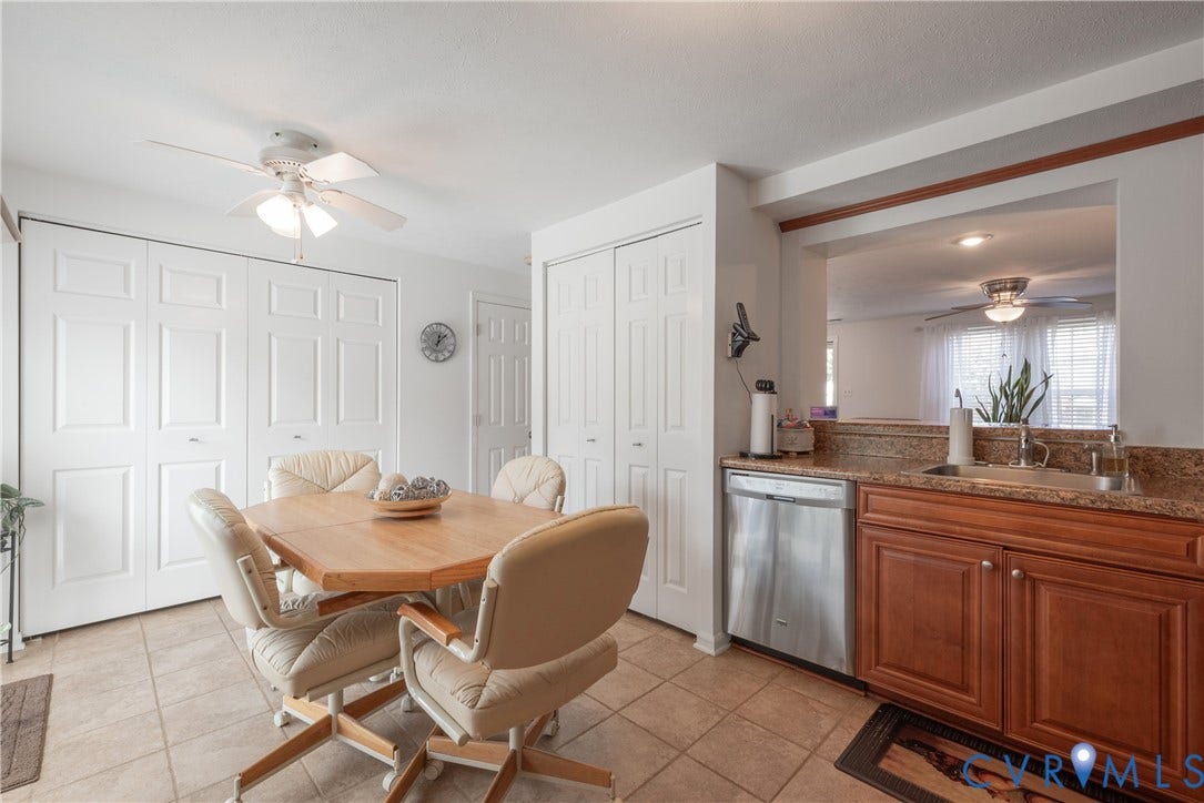 Tiled flooring, wood-finish cabinetry, stainless steel dishwasher, kitchen pass-through, and ceiling fan