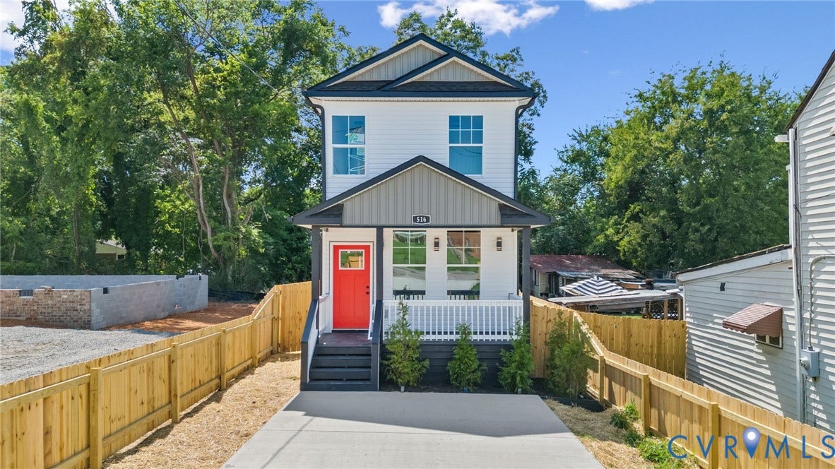 516 S South Street, Myers, Petersburg, VA 23803 Two-story exterior with white siding and dark trim, featuring a concrete driveway, a wood fence, and a vibrant red entry door