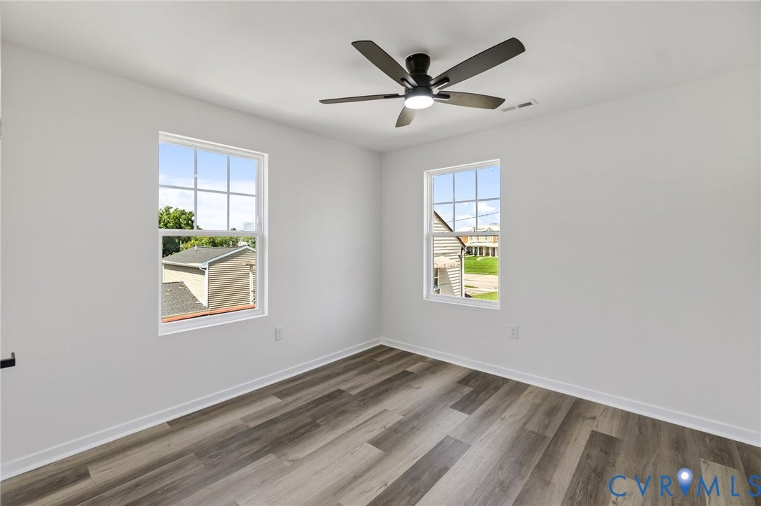 516 S South Street, Myers, Petersburg, VA 23803 Room featuring wood-finish flooring, white walls, two windows with white trim, and a ceiling fan with integrated lighting