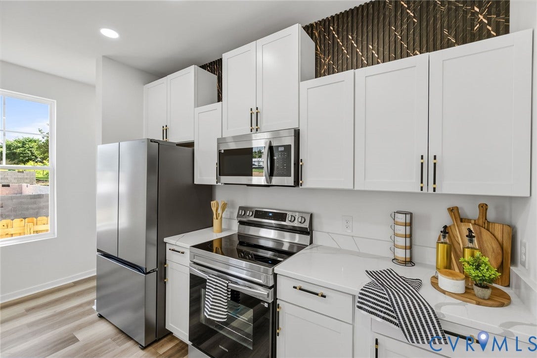 516 S South Street, Myers, Petersburg, VA 23803 White cabinetry with gold-tone hardware, stainless steel appliances, light-toned countertops, and wood-finish flooring