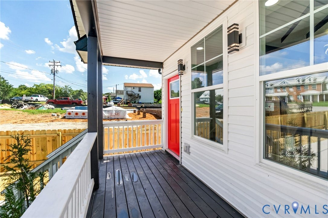 516 S South Street, Myers, Petersburg, VA 23803 Front porch with dark wood-finish decking, white railings, a vibrant red door, and modern exterior sconces