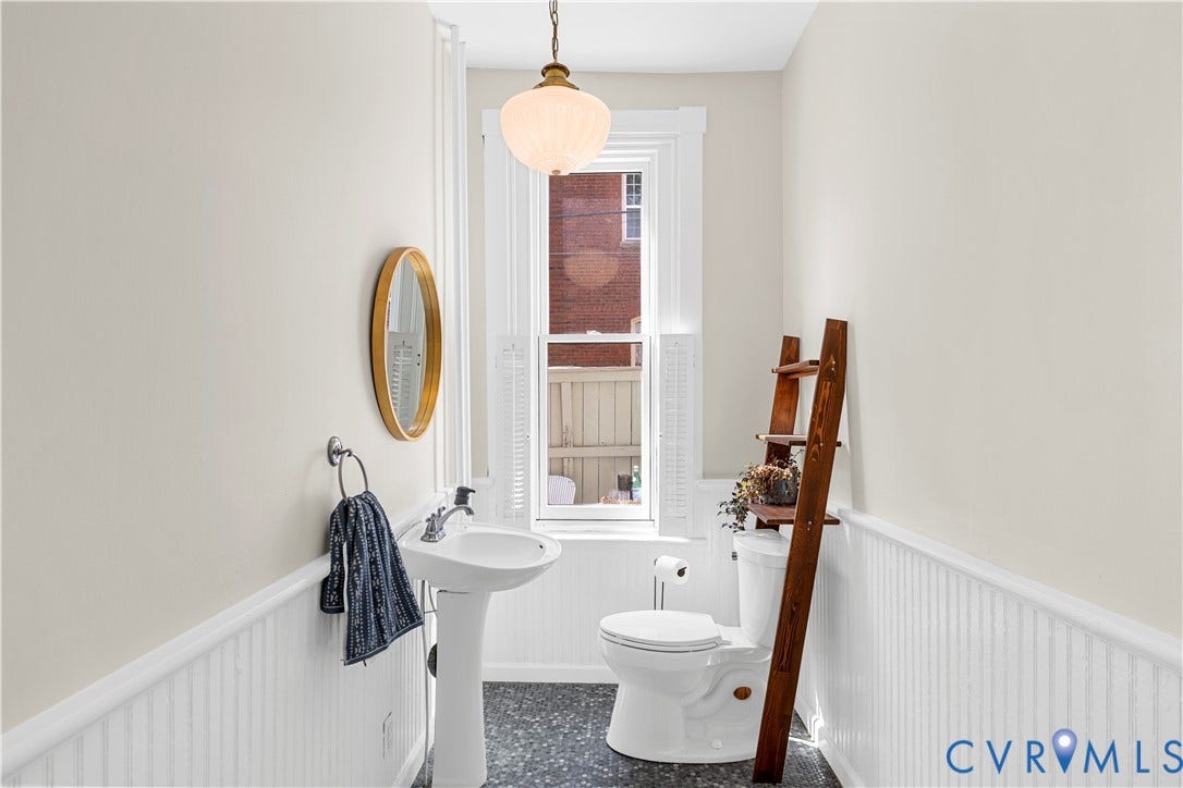 109 N Morris Street, The Fan, Richmond, VA 23220 White pedestal sink, wall-mounted oval mirror, beadboard wainscoting, and a window with white shutters