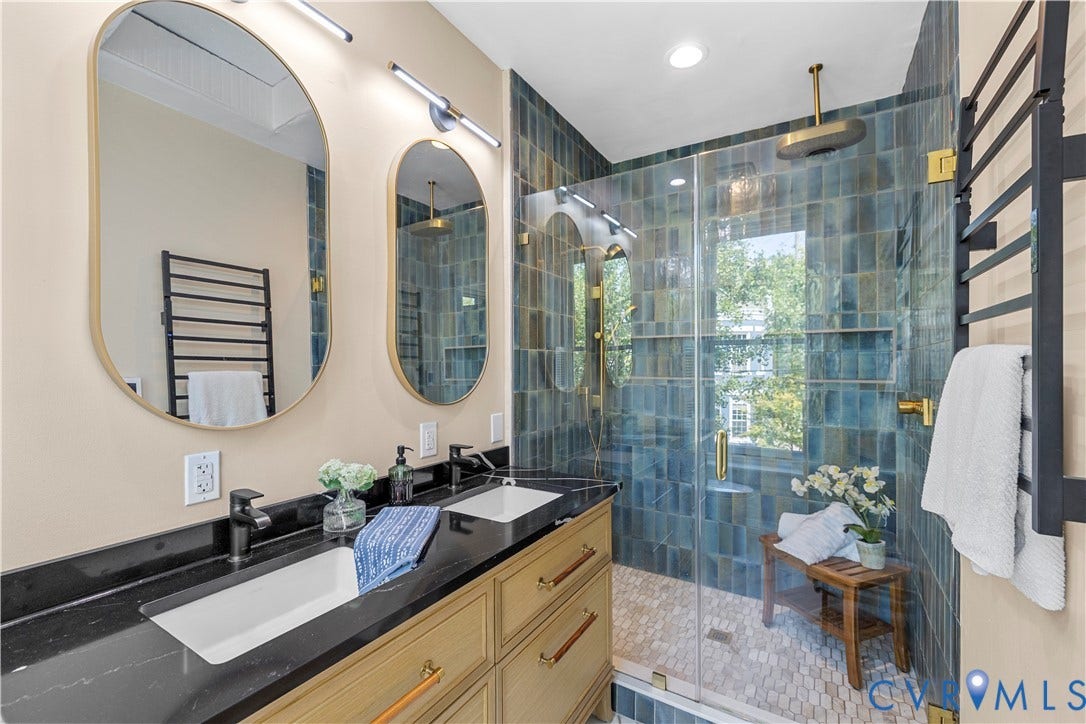 109 N Morris Street, The Fan, Richmond, VA 23220 Dual vanity with black countertops and integrated sinks, glass-enclosed shower with blue-toned tile, ceiling-mounted showerhead, and a wall-mounted towel warmer